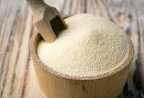 Wooden scoop filled with white powder on a wooden surface